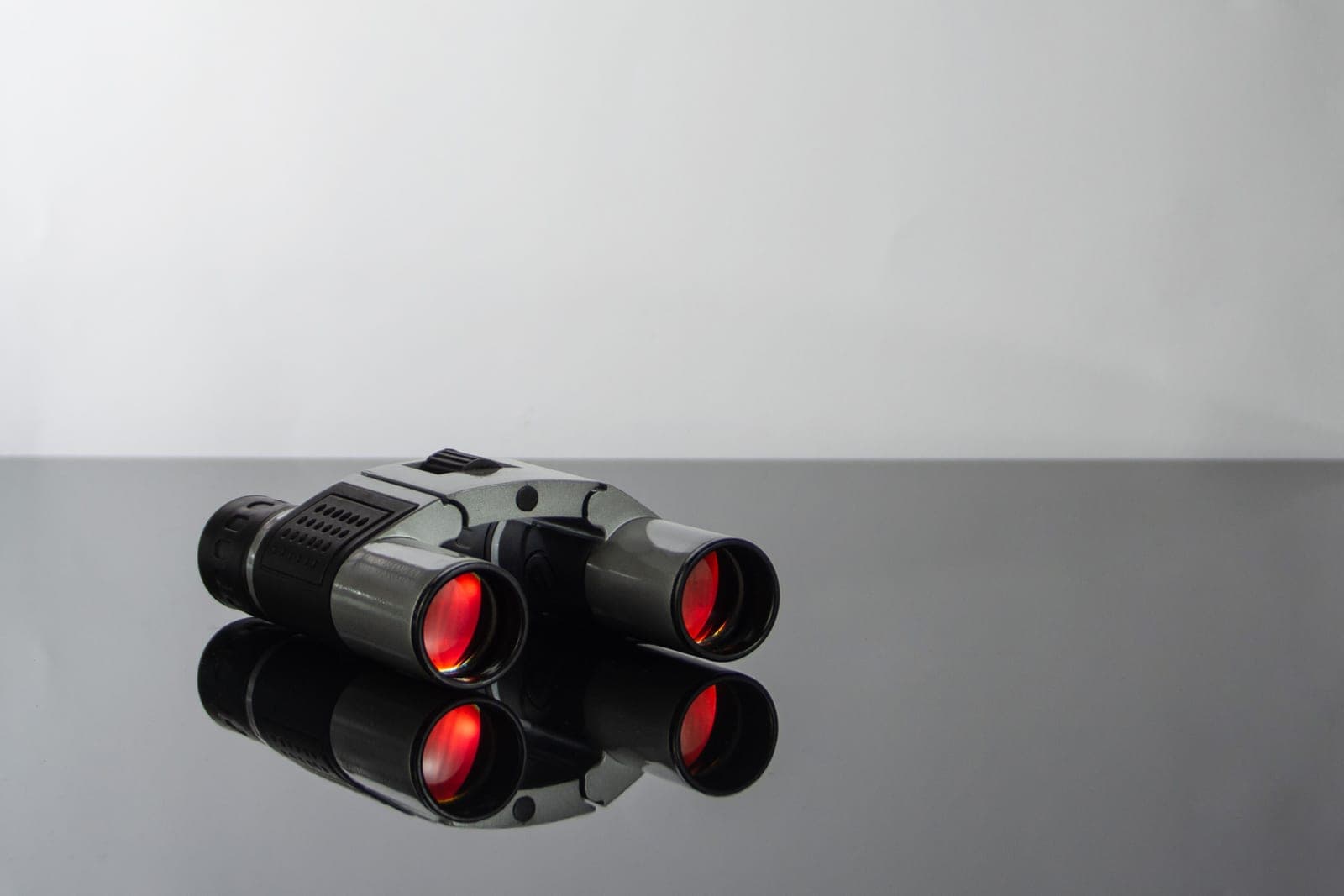 Two pairs of binoculars side by side on a wooden table.