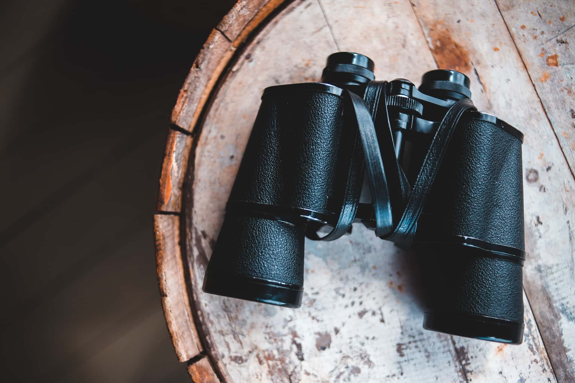 A camera lens and a pair of binoculars laid side by side on a table.