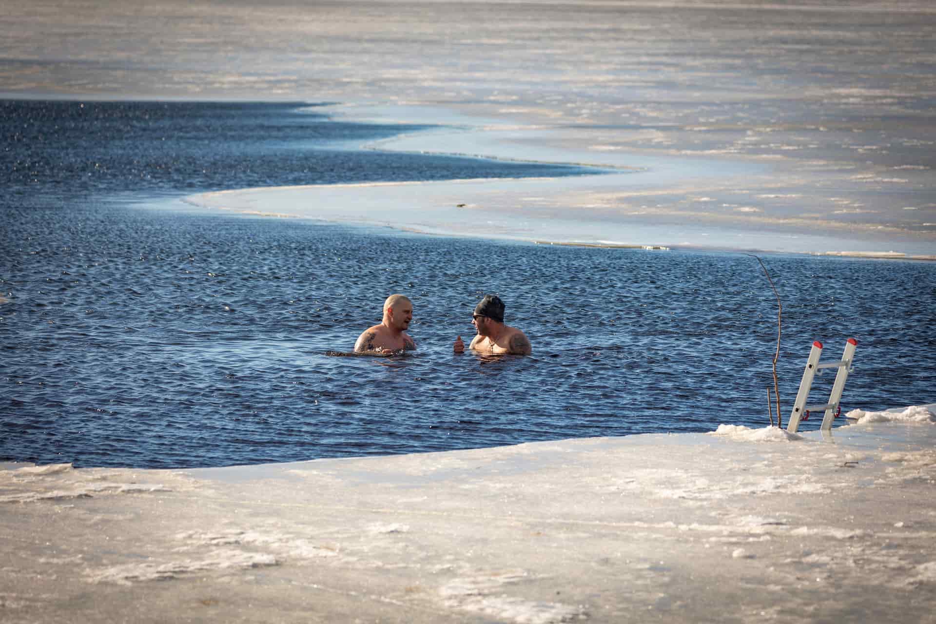 Partly frozen water in a shallow basin, ice ringing the edge and open water at the center.