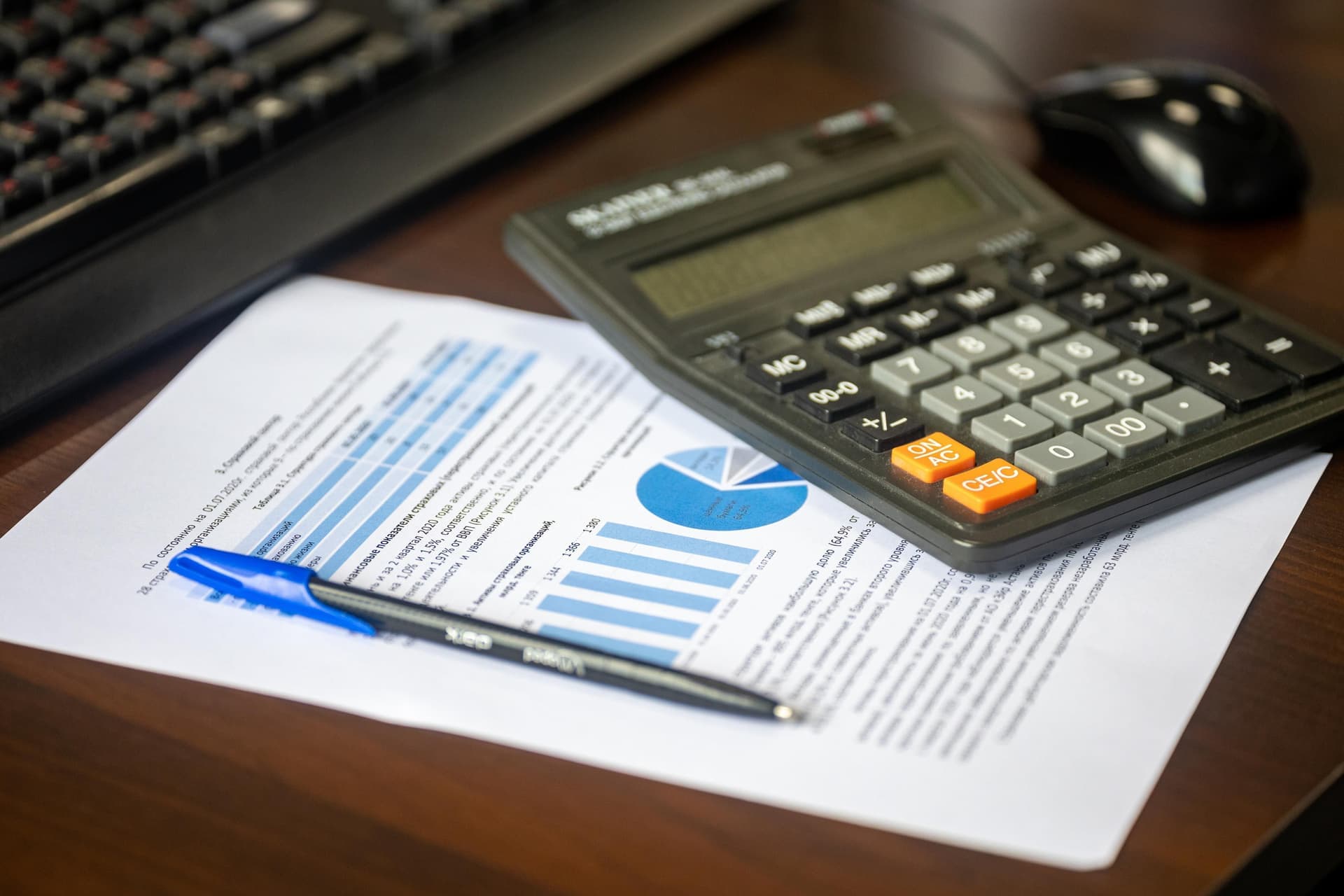 A calculator and a sheet of figures on a desk.