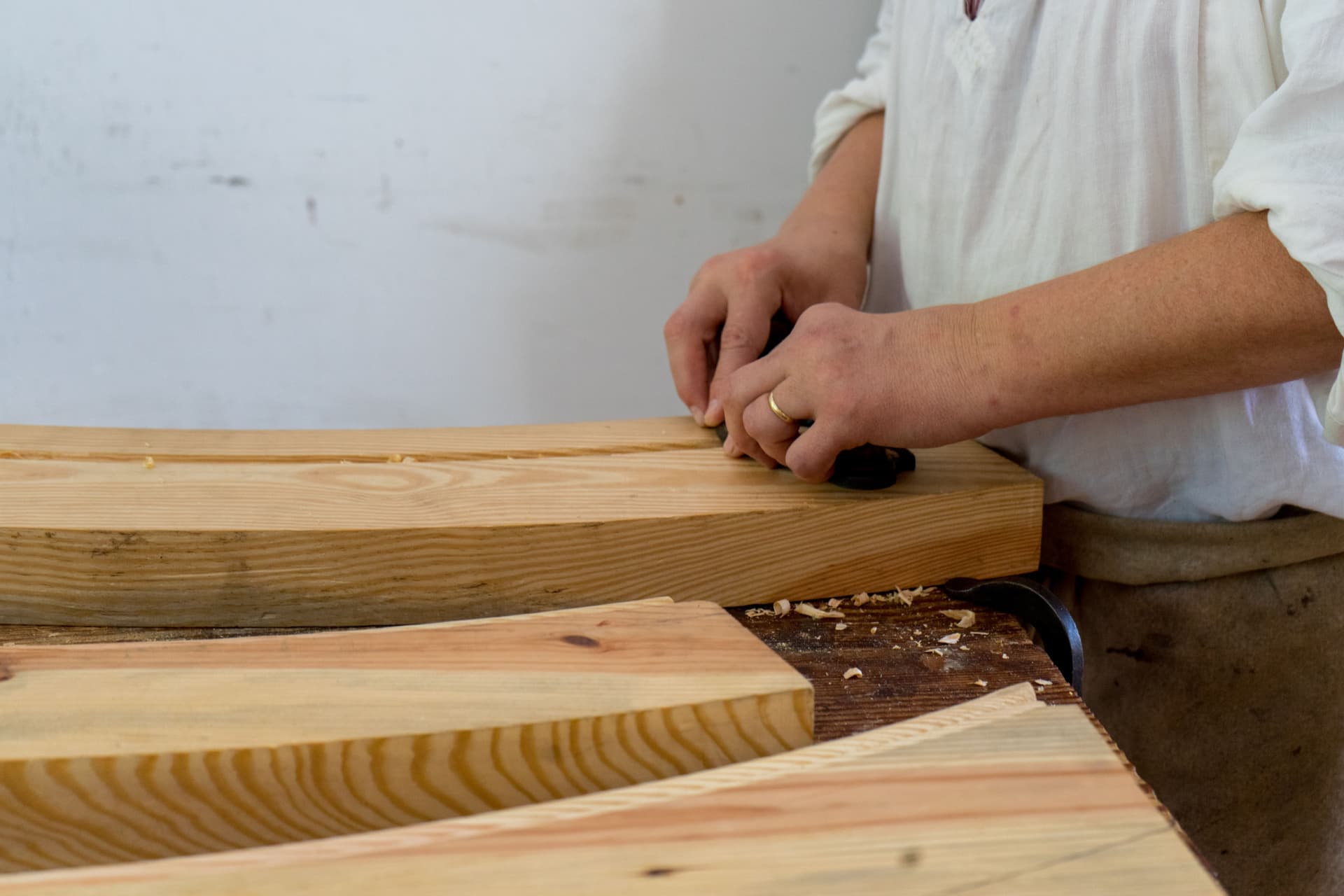 Hand tools and a pine plank laid out on a workshop bench.