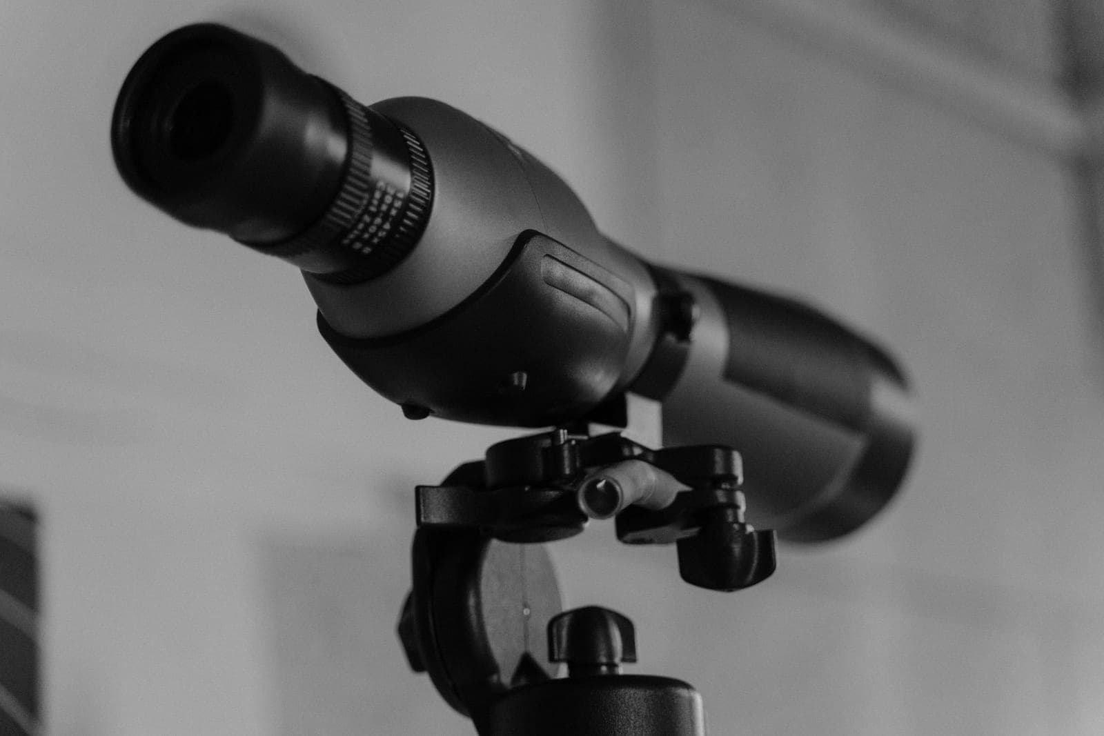 A close-up of an angled spotting scope mounted on a tripod head.